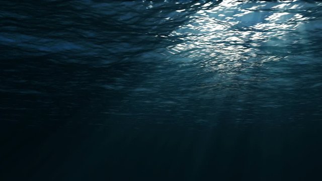 The camera moves forward under the surface of the water. Underwater view. Sun rays through ocean or sea surface.