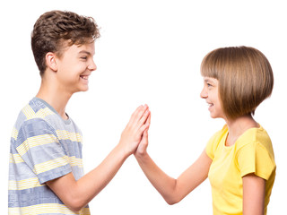Friendship teen boy and girl are banging their palms. Portrait of happy brother and sister palm bump isolated on white background. Funny couple children gesturing and greeting.