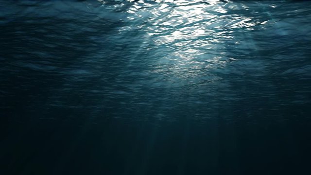 The camera moves forward under the surface of the water. Underwater view. Sun rays through ocean or sea surface. Underwater ocean waves ripple, high quality.