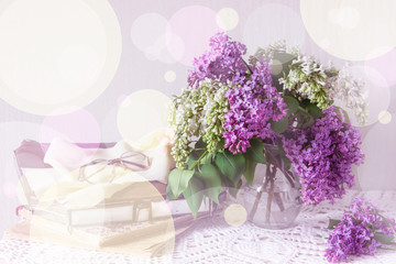 A bouquet of lilac and a vintage handbag, books, glasses on a knitted tablecloth, toning. Sunny summer day.