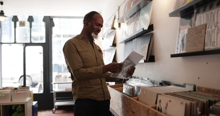 Senior male looking for records in a store - Powered by Adobe