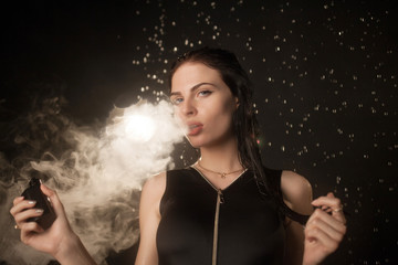 Young beautiful woman vaping e-cigarette in rain. Water flowing on woman face.