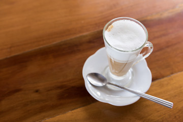 Hot latte coffee in long cup on wooden table
