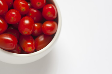 Close-up shot of some red plum tomatoes in a round white bowl