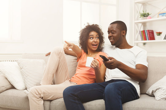 Happy african-american couple watching TV at home