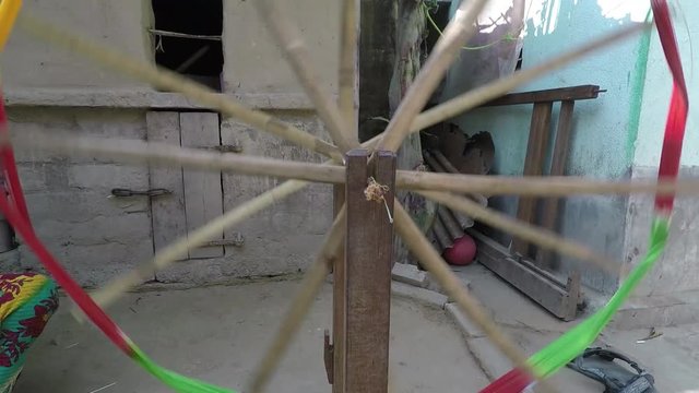Pretty young woman turns spindle and spinning wheel, track out from spinning wheel to medium shot. 2X slow motion. Bengal, India