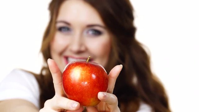 Young brunette woman recommend healthy eating diet, holding red apple in hands, focus on fruit, isolated on white.
