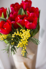 A inviting bunch of red tulips and yellow mimose are in vase