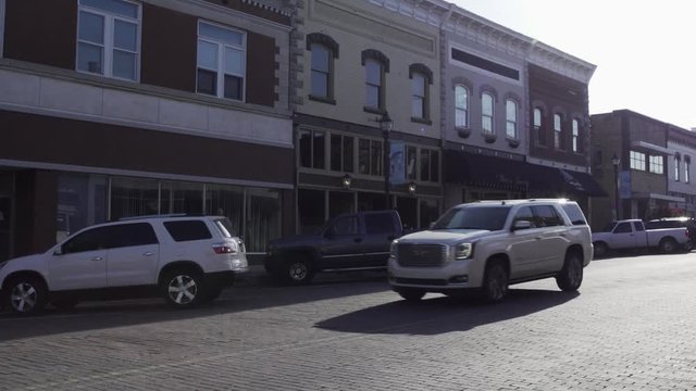 Cars Drive Down A Cobbled Street In A Small Town In America