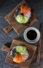 Sushi donuts set with salmon, vegetarian with soy sauce. Sushi trend. Creative food. Dark background