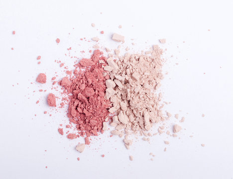 Closeup of crushed eyeshadows, blushes or powders scattered on white background. Copy space. Flat lay. Top view