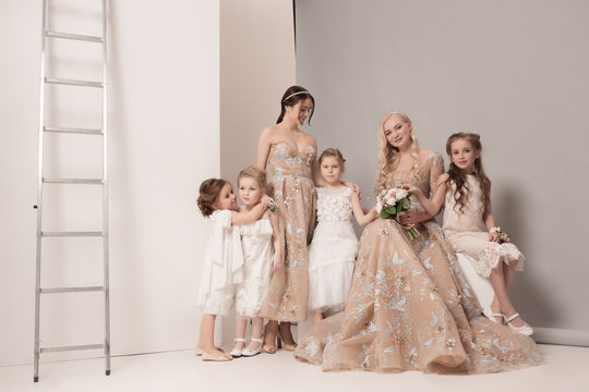 Little pretty girls with flowers dressed in wedding dresses