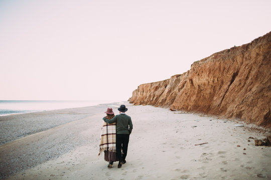 A young couple is walking on the sea coastline. Romantic date on the beach. Rear view