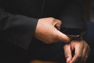 African american man in black suit using mobile device