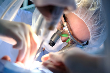 Female dentist in surgical uniform at the clinic while performing surgery for the patient