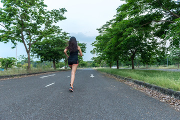 Beautiful asian woman jogging on the road for burn fat in the park
