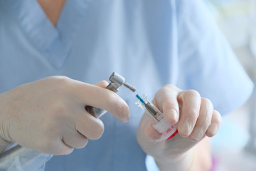 Hands of a dental surgeon in protective gloves with a surgical instrument