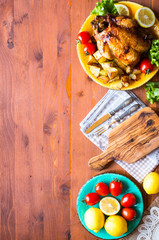 Homemade baked chicken with lemon and potatoes on a wooden background