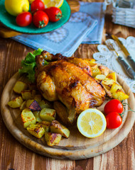 Homemade baked chicken with lemon and potatoes on a wooden background