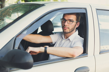 Young thoughtful man driving a car