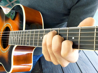 Fototapeta premium Acoustic guitar. A man plays an guitar with two hands close-up picture