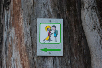 Municipal plate indicating direction for a easy walk in the mountains hanging on a log