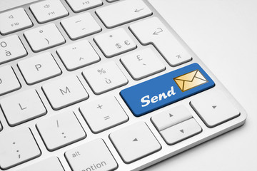 Send blue button with a mail icon on a white isolated keyboard.