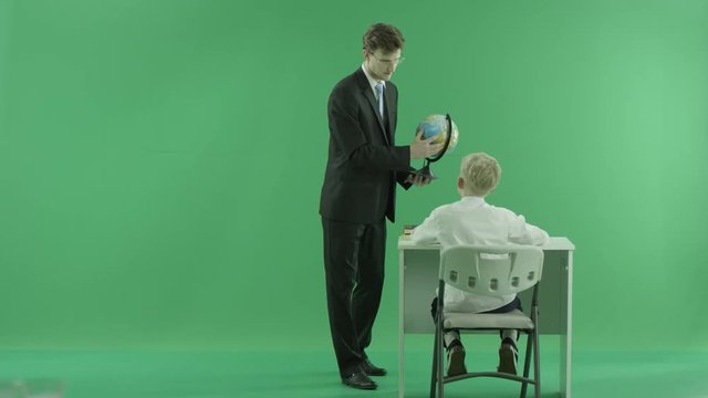 a teacher shows something on the globe to his pupil on green screen