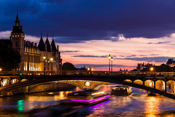 Fototapeta premium Night view of Conciergerie Castle and Pont Notre-Dame bridge over river Seine. Paris, France