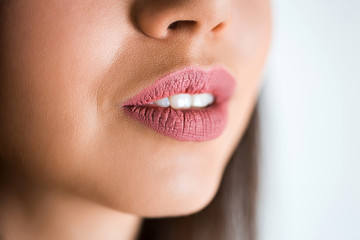 Fototapeta premium Closeup of sexy open lips of woman on white background. Pink lipstick, lip gloss on the lips. Beautiful smile.