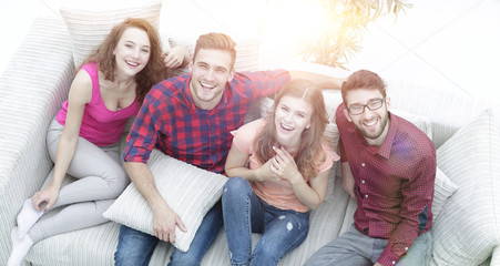 view from the top.the four friends laugh, sitting on the sofa