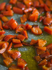 Cooking red bell peppers in a skillet with olive oil