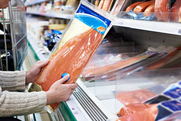 Une femme achète du poisson rouge légèrement salé en magasin