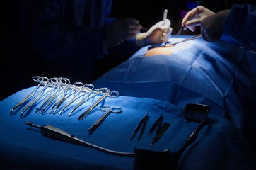 selective focus surgical instrument lying on table while group of surgeon work in operation room at hospital, emergency case, surgery, medical technology, health care cancer, disease treatment concept