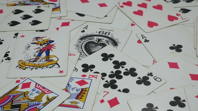 One hundred dollar bills, deck of poker cards, red, green, blue and black casino chips and two red dice rotating on green table, poker game, gambling. Close up, seamless loop, 4K Ultra HD.