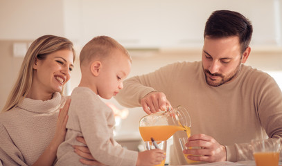 Family make fresh orange juice in their kitchen.