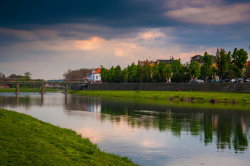 River Uzh in Ukraine, Uzhgorod. Trees, city, bridge and cloudy sky reflected in water