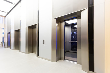 Modern steel elevator open 50% cabins in a business lobby or Hotel, Store, interior, office,perspective wide angle. Three elevators in hotel lobby..