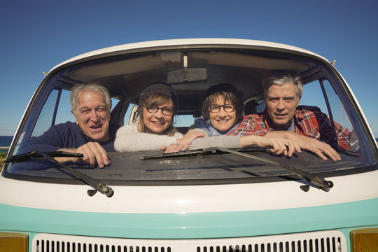 Portrait of senior people through vintage camper van windshield