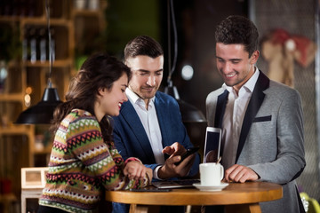 Young Man Showing Mobile phone to his Friends in a Cafe