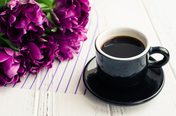 Obraz na płótnie Canvas Cup of coffee with bouquet of purple tulips