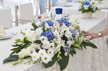 Wedding bouquet on the table of the bride and groom from white feces and gently blue flowers