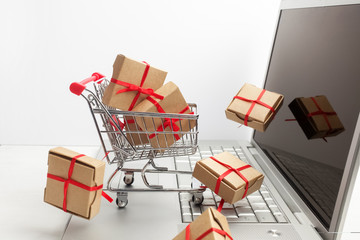 Paper boxes in a shopping cart on a laptop keyboard. Ideas about e-commerce, a transaction of buying or selling goods or services online.