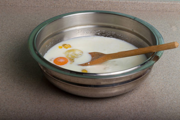 broken chicken eggs in a plate with milk and spices. Making an omlet.