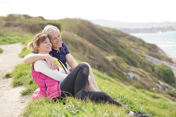 Naklejka na ściany i meble Senior couple relaxing by the coast admiring the ocean view