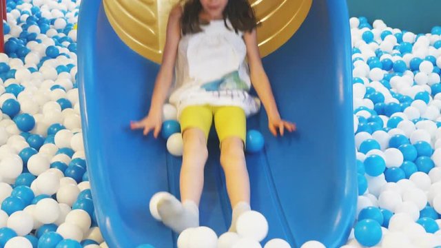 Cute smiling little girl having fun on slide in playroom.