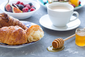  Breakfast concept close up with honey, croissants and a cup of coffee.