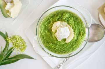 Cream soup of broccoli, avocado and cauliflower with whipped cream on a wooden table. The view from the top.