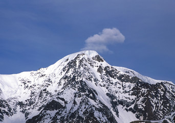 Fototapeta na wymiar Snow-capped mountain with single cloud on top