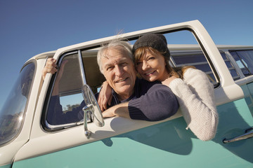 Happy senior couple traveling with vintage van by the ocean